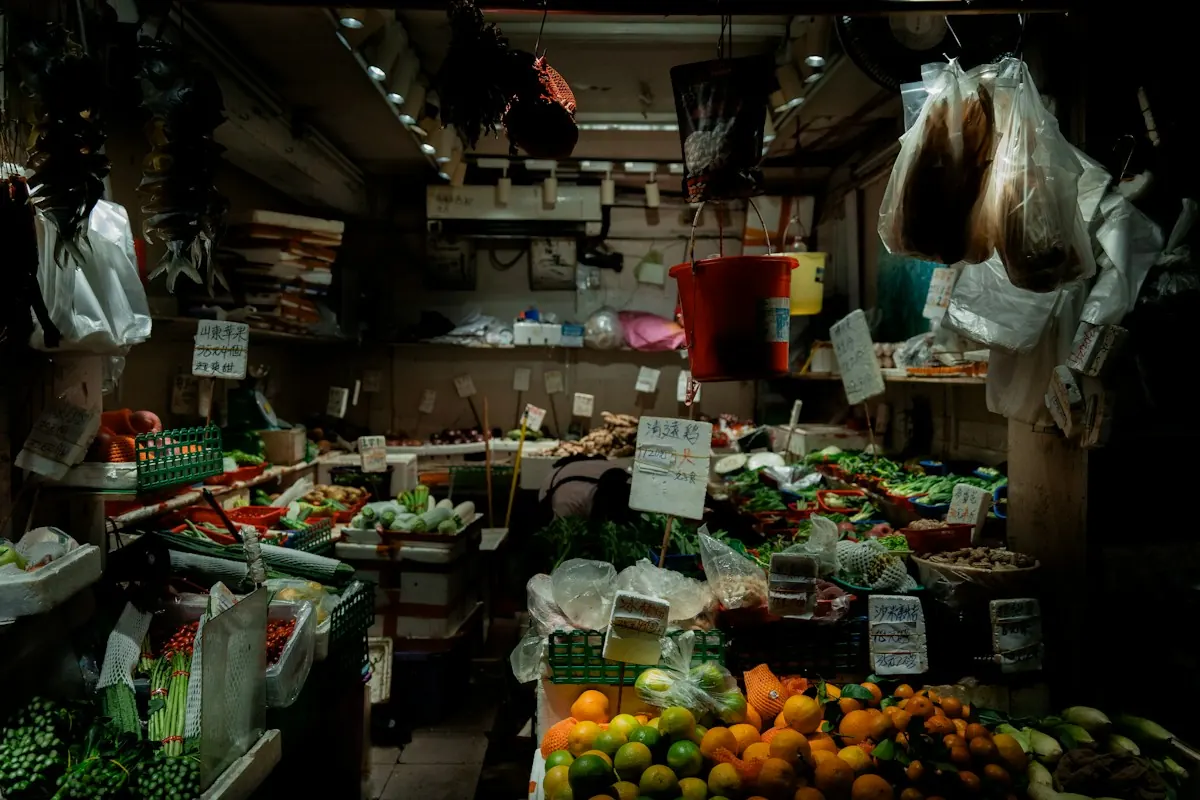 A late-night produce stall packed with leafy greens, citrus and hanging bags